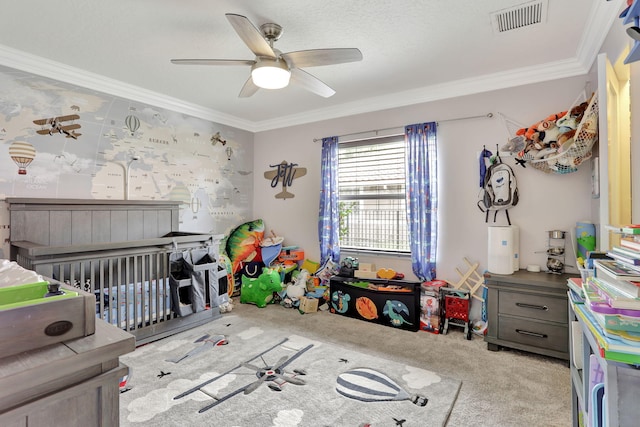 carpeted bedroom with visible vents, crown molding, a crib, and ceiling fan