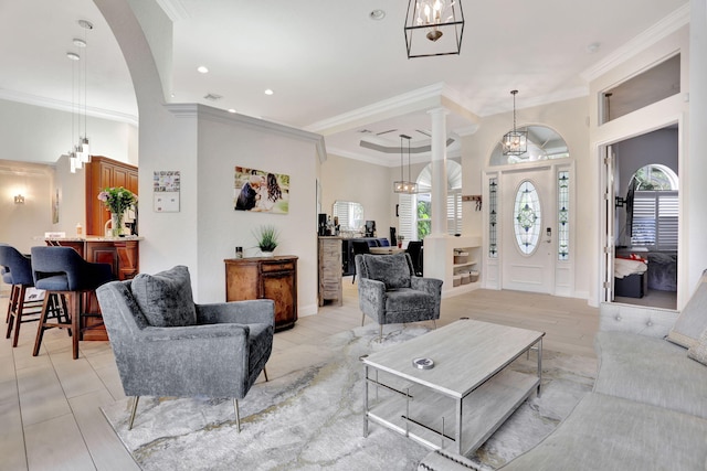 living room featuring ornamental molding, a healthy amount of sunlight, and decorative columns