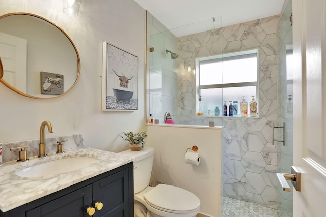 full bath with a marble finish shower, vanity, and toilet