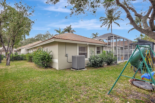 exterior space with central AC unit, a lawn, a playground, and stucco siding