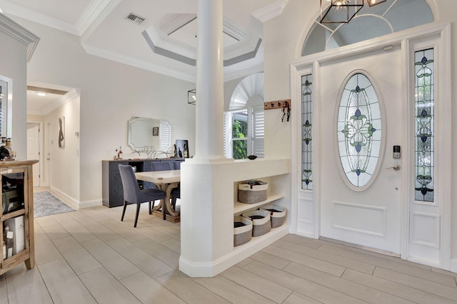 foyer entrance featuring baseboards, visible vents, wood finish floors, and ornamental molding