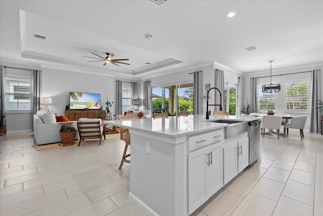 kitchen featuring sink, decorative light fixtures, white cabinetry, ceiling fan with notable chandelier, and a kitchen island with sink