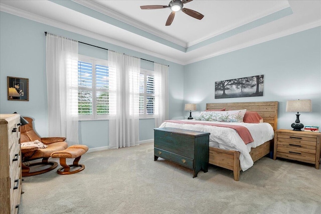 carpeted bedroom with ceiling fan, crown molding, and a tray ceiling