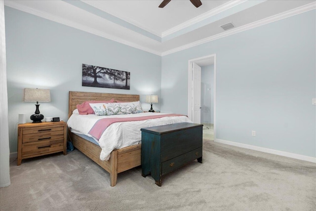 carpeted bedroom with ceiling fan, crown molding, a raised ceiling, and ensuite bath