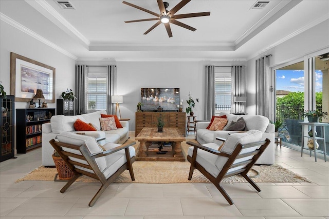 living room featuring light tile patterned floors, ceiling fan, a tray ceiling, and crown molding