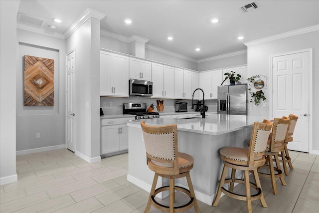 kitchen featuring a center island with sink, a breakfast bar area, appliances with stainless steel finishes, white cabinetry, and sink