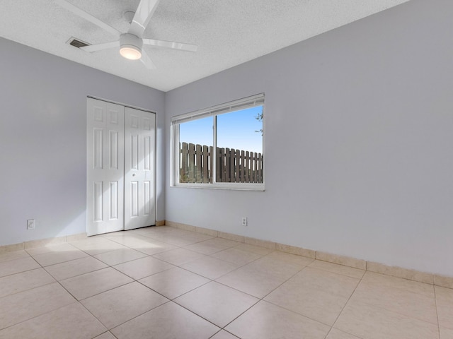 unfurnished bedroom with a textured ceiling, a closet, ceiling fan, and light tile patterned flooring