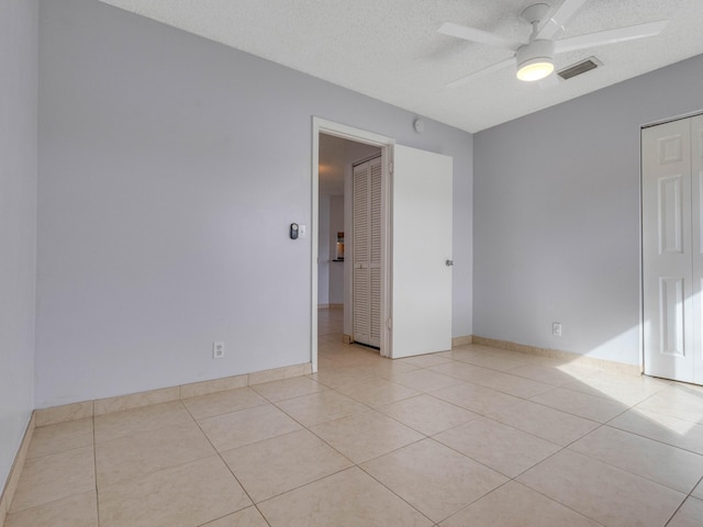 tiled empty room with ceiling fan and a textured ceiling