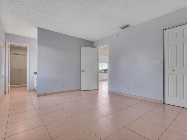 spare room with light tile patterned floors and a textured ceiling