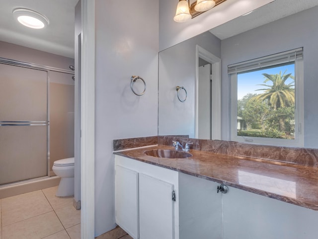 bathroom with tile patterned floors, vanity, toilet, and a shower with shower door