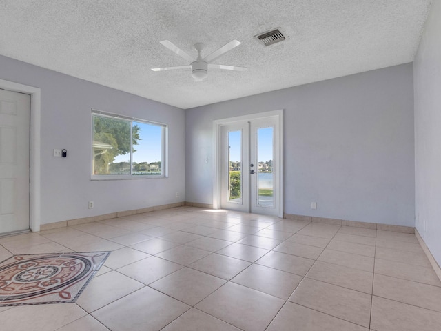 tiled empty room featuring french doors, a textured ceiling, plenty of natural light, and ceiling fan