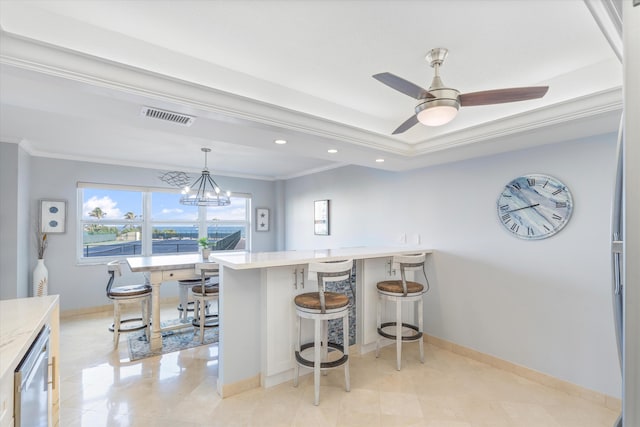 kitchen with decorative light fixtures, a kitchen bar, ceiling fan with notable chandelier, ornamental molding, and light tile patterned flooring