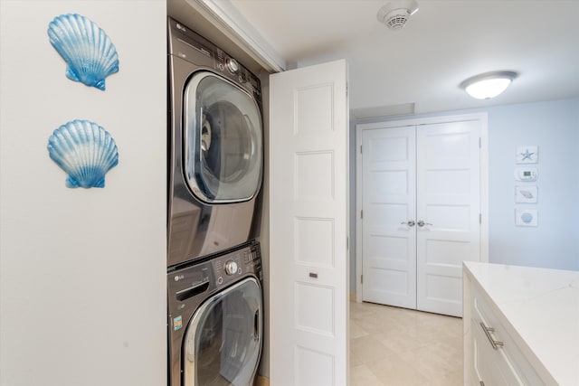 laundry area with stacked washer / dryer and light tile patterned floors