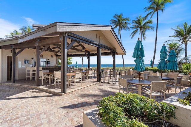 surrounding community with an outdoor bar, a water view, and a patio