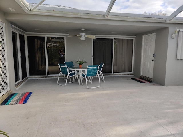 view of patio featuring ceiling fan and glass enclosure