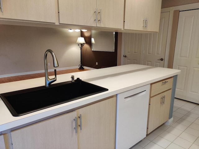 kitchen with light brown cabinetry, sink, light tile patterned floors, and dishwasher