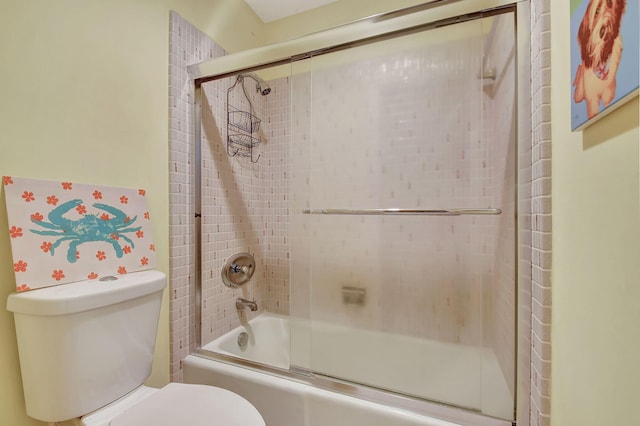 bathroom with toilet and bath / shower combo with glass door