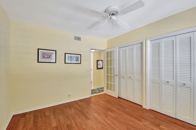 unfurnished bedroom featuring ceiling fan, multiple closets, and light hardwood / wood-style floors