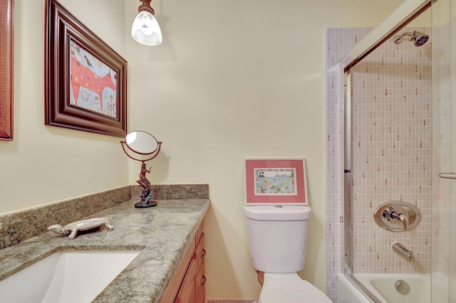 full bathroom with bath / shower combo with glass door, toilet, and vanity