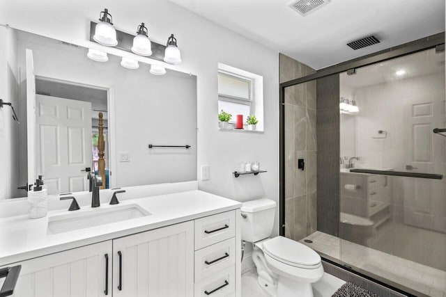 bathroom featuring vanity, a healthy amount of sunlight, an enclosed shower, and toilet