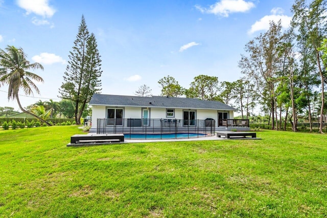 rear view of house with a lawn and a pool side deck