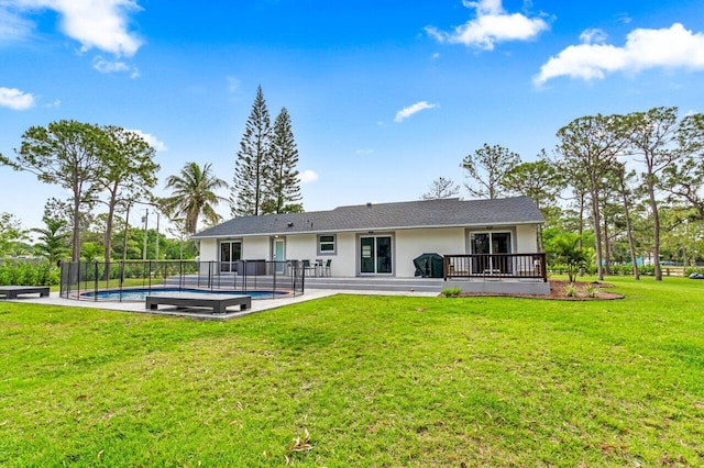 rear view of house with a lawn, a pool side deck, and a patio