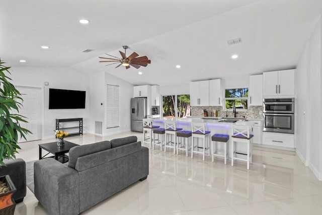 living room featuring light tile patterned floors, ceiling fan, lofted ceiling, and sink