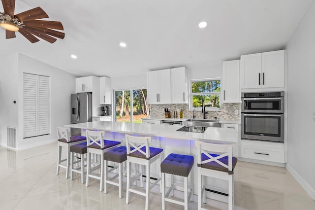 kitchen with white cabinets, a kitchen breakfast bar, a center island, and appliances with stainless steel finishes