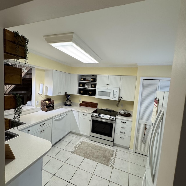 kitchen with white appliances, ornamental molding, light tile patterned floors, and white cabinetry