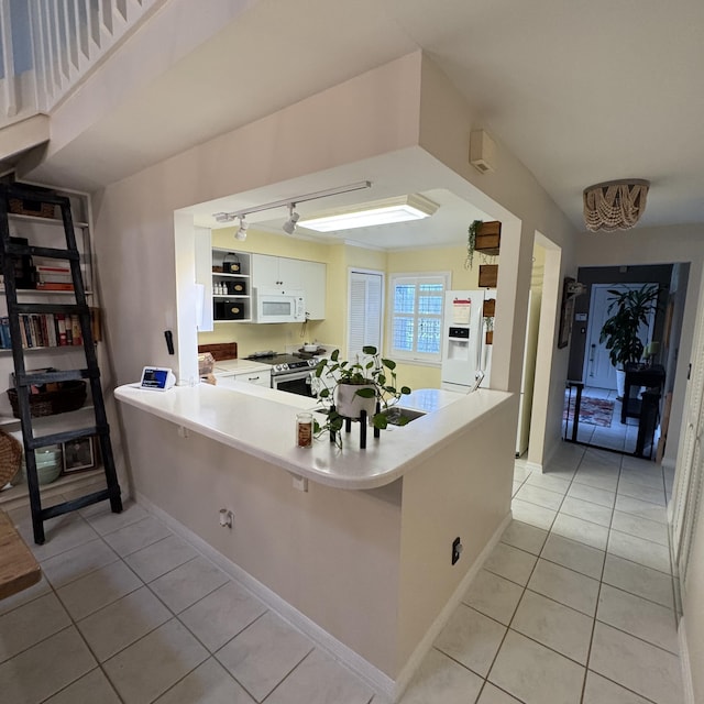 kitchen featuring white appliances, white cabinets, kitchen peninsula, and light tile patterned floors