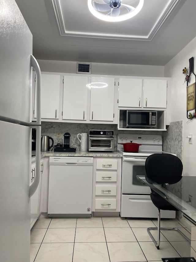 kitchen featuring decorative backsplash, light tile patterned floors, white cabinets, and white appliances