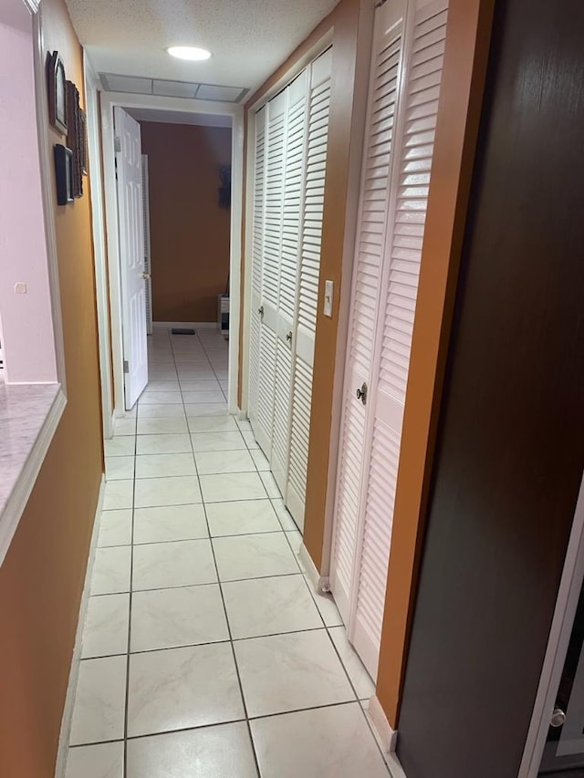 hallway featuring light tile patterned floors and a textured ceiling