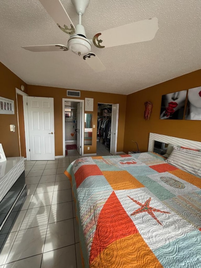 bedroom with a textured ceiling, ceiling fan, a spacious closet, tile patterned flooring, and a closet