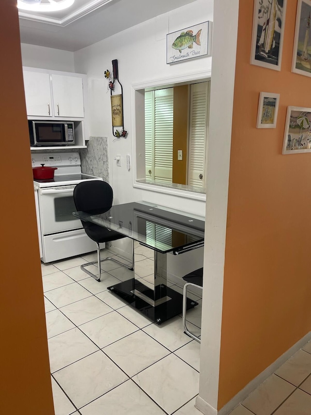 kitchen with white cabinets, light tile patterned floors, and white range with electric stovetop