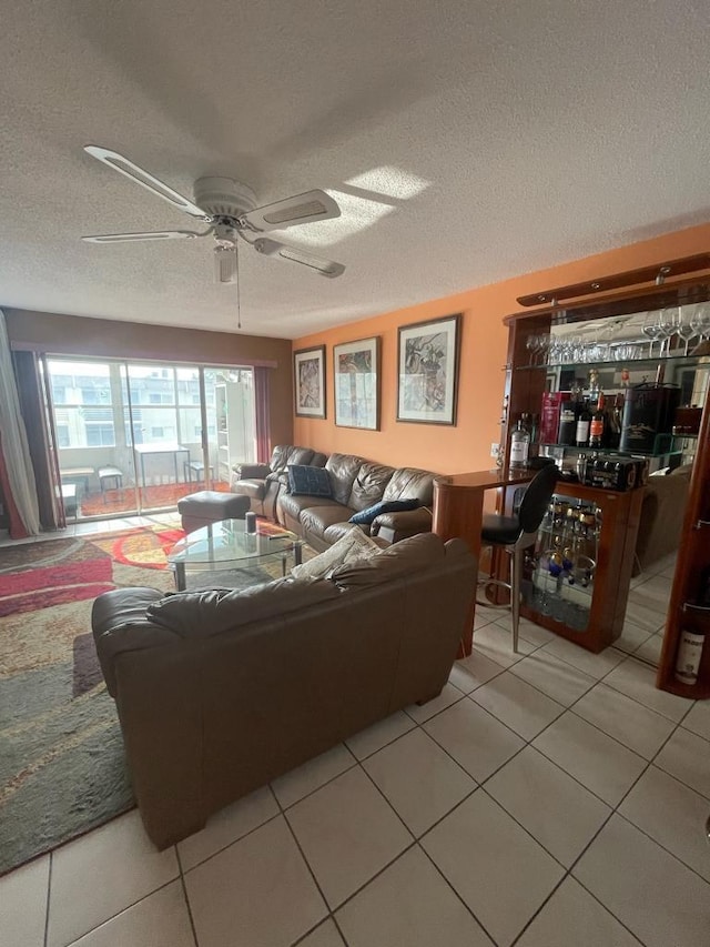 tiled living room with bar, a textured ceiling, and ceiling fan