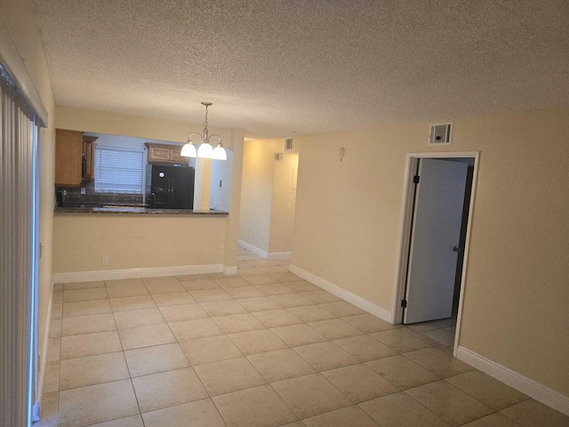 unfurnished room featuring light tile patterned flooring, a textured ceiling, and a chandelier