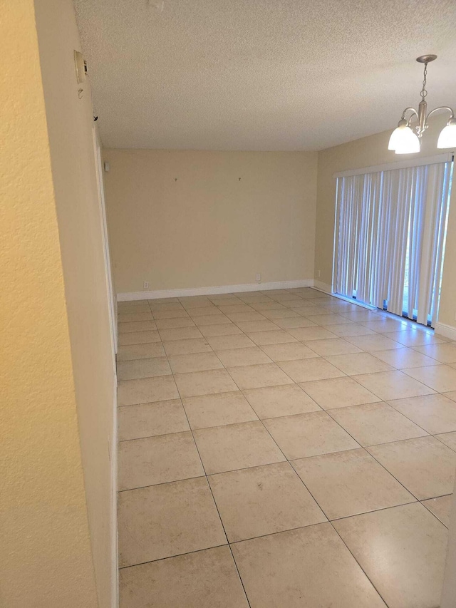 unfurnished room featuring light tile patterned floors, a textured ceiling, and a notable chandelier