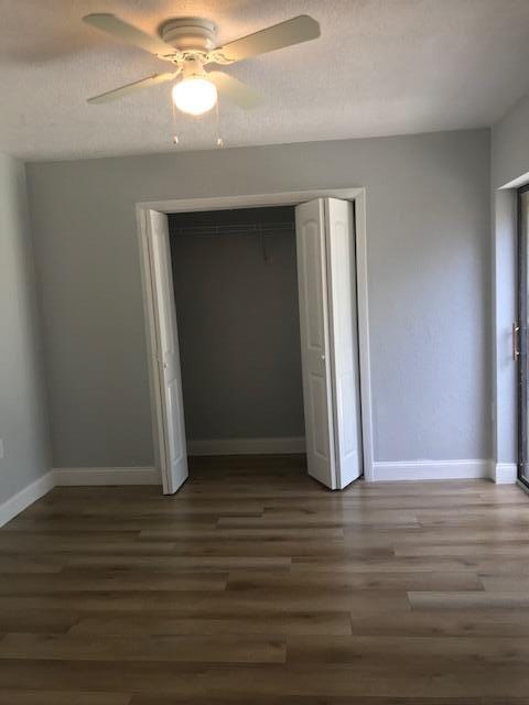 unfurnished bedroom with ceiling fan, a closet, and dark hardwood / wood-style floors