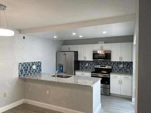 kitchen featuring white cabinets, appliances with stainless steel finishes, kitchen peninsula, and sink