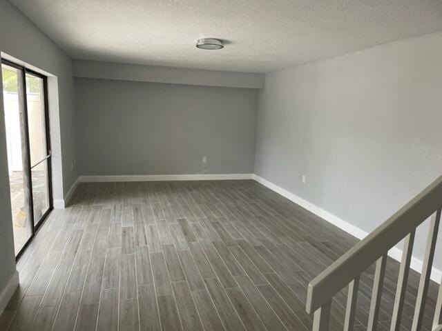 empty room with a textured ceiling and dark wood-type flooring