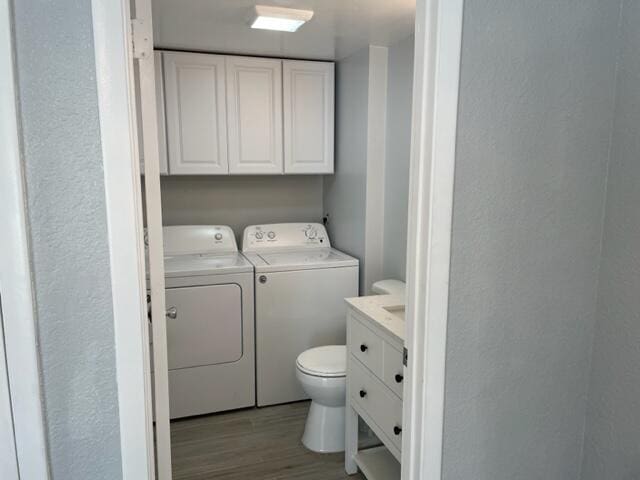 clothes washing area featuring light hardwood / wood-style floors, cabinets, and separate washer and dryer