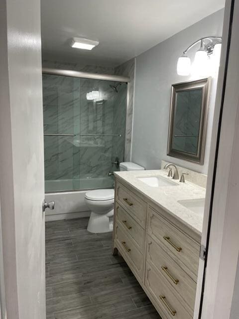 full bathroom with vanity, toilet, and bath / shower combo with glass door