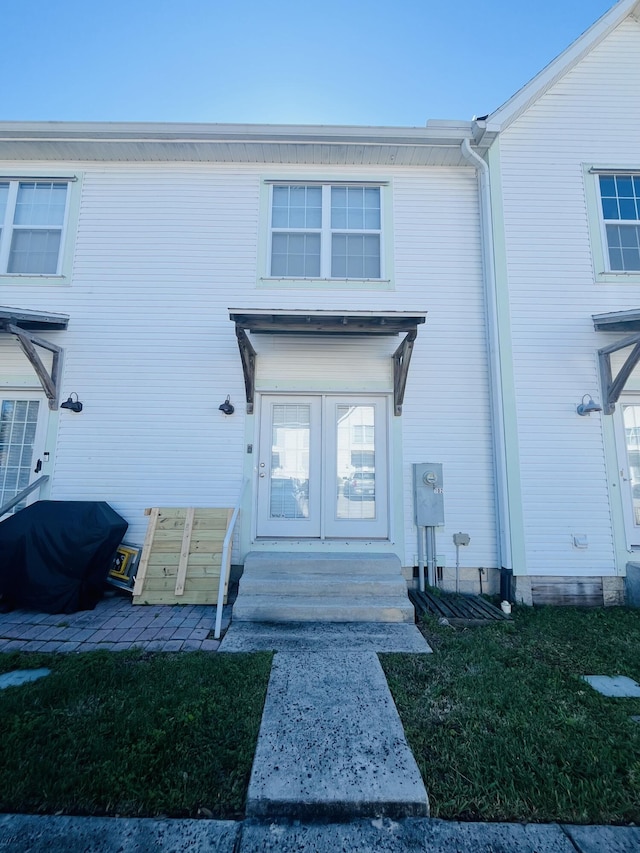 doorway to property with a lawn and french doors