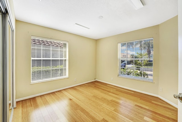 spare room with a healthy amount of sunlight and hardwood / wood-style floors