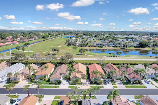 drone / aerial view featuring golf course view, a residential view, and a water view