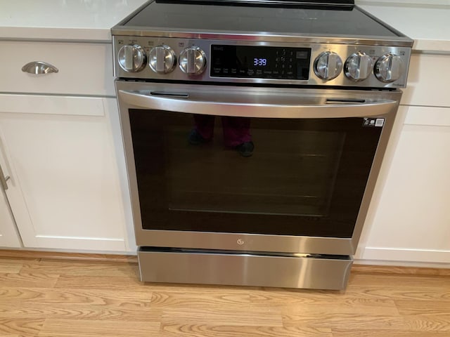 details with stainless steel range with electric stovetop and white cabinetry