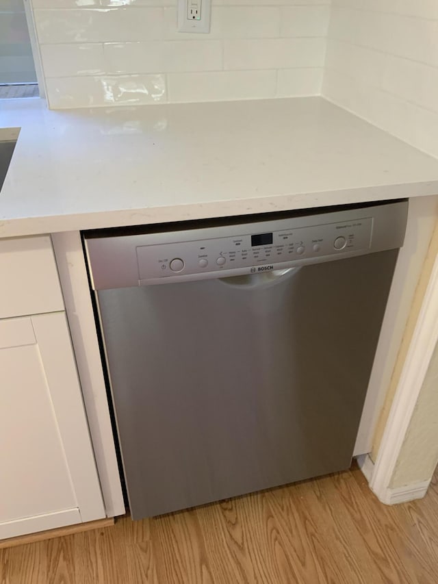 room details featuring stainless steel dishwasher, white cabinets, and light hardwood / wood-style flooring