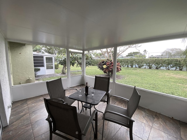 sunroom featuring a water view