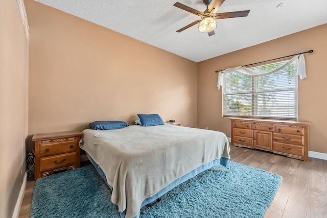 bedroom featuring ceiling fan, light hardwood / wood-style floors, and a textured ceiling