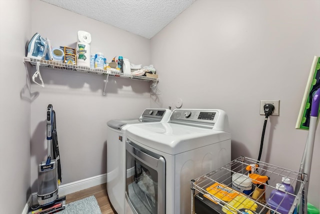 clothes washing area featuring a textured ceiling, washing machine and clothes dryer, and wood-type flooring